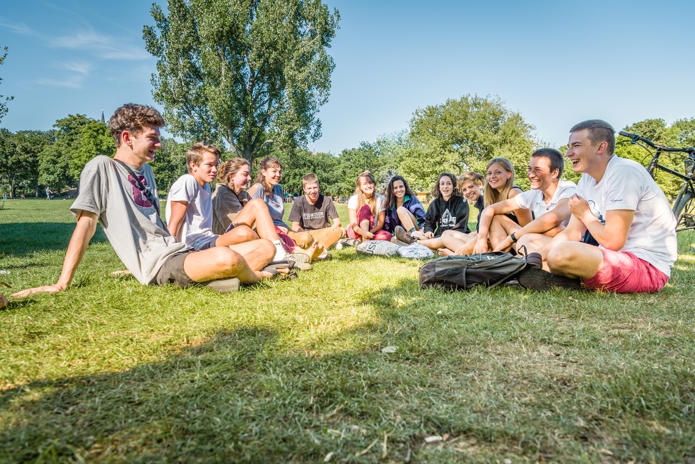 Studierende sitzen im Gras zusammen