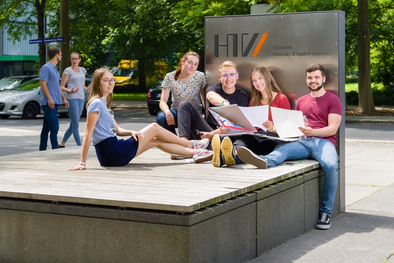 Gruppe Studierende sitzen vor dem Campus