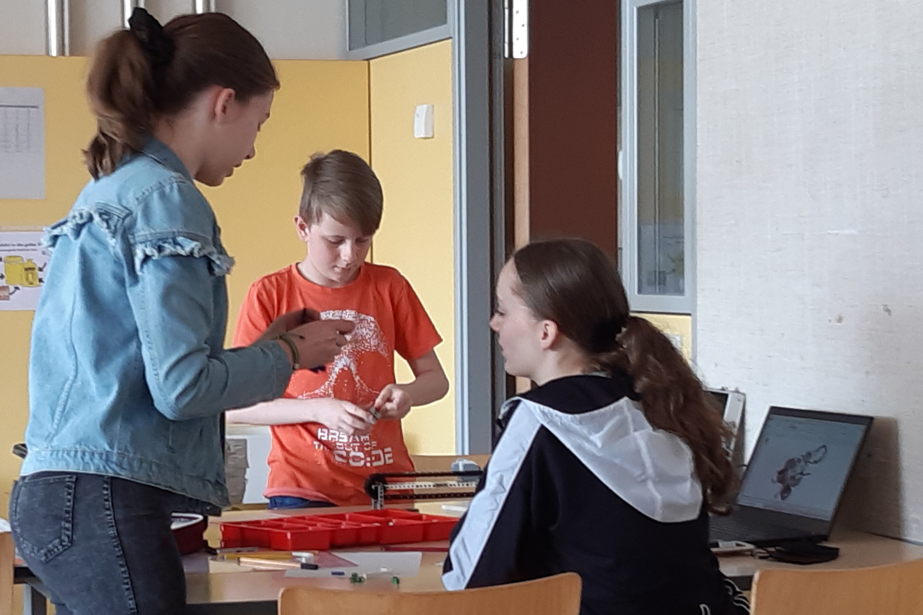 drei Schülerinnen und Schüler beim Legobasteln