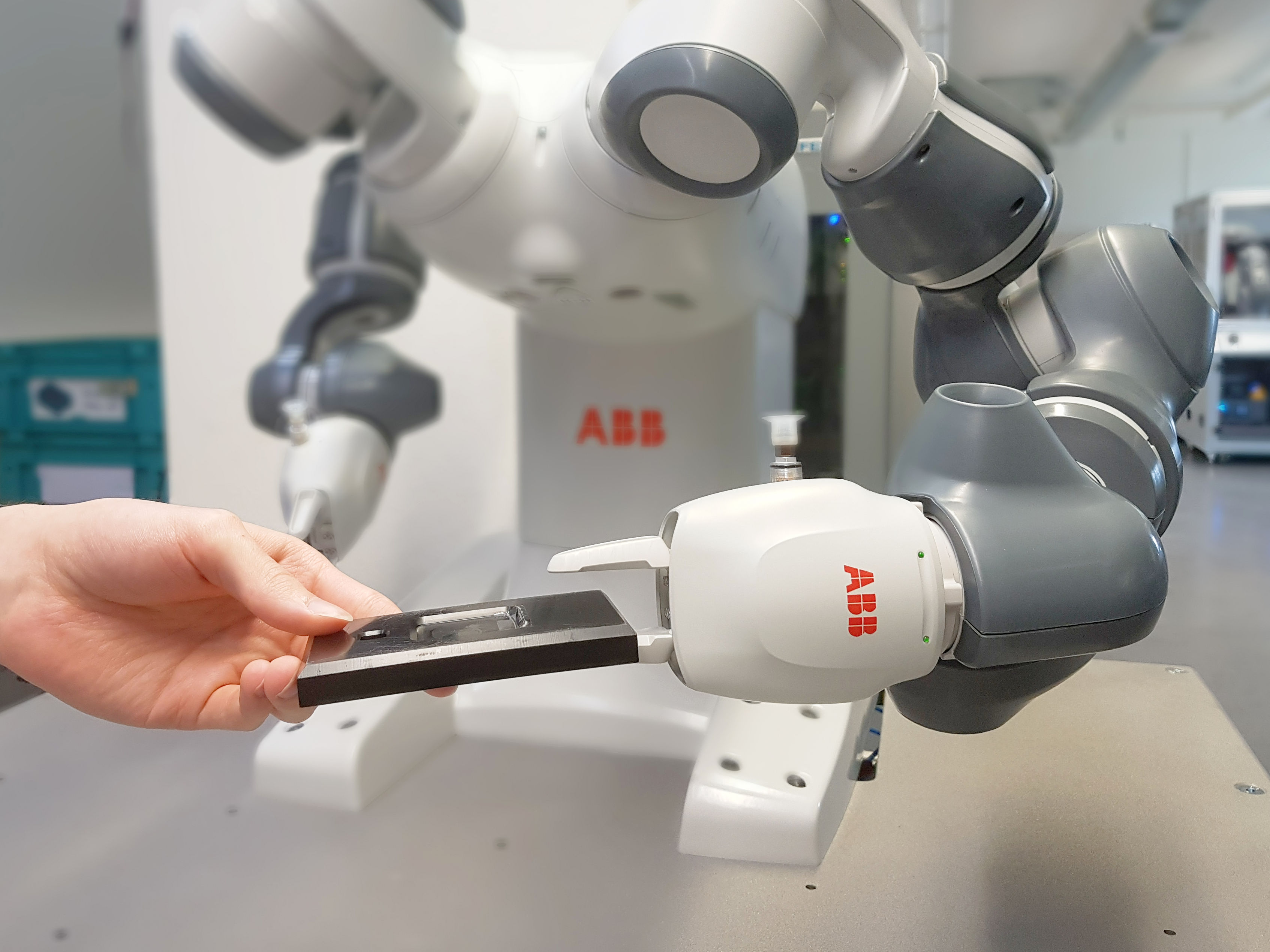 Mitarbeiter reicht einem Roboter eine Gehäuseunterschale