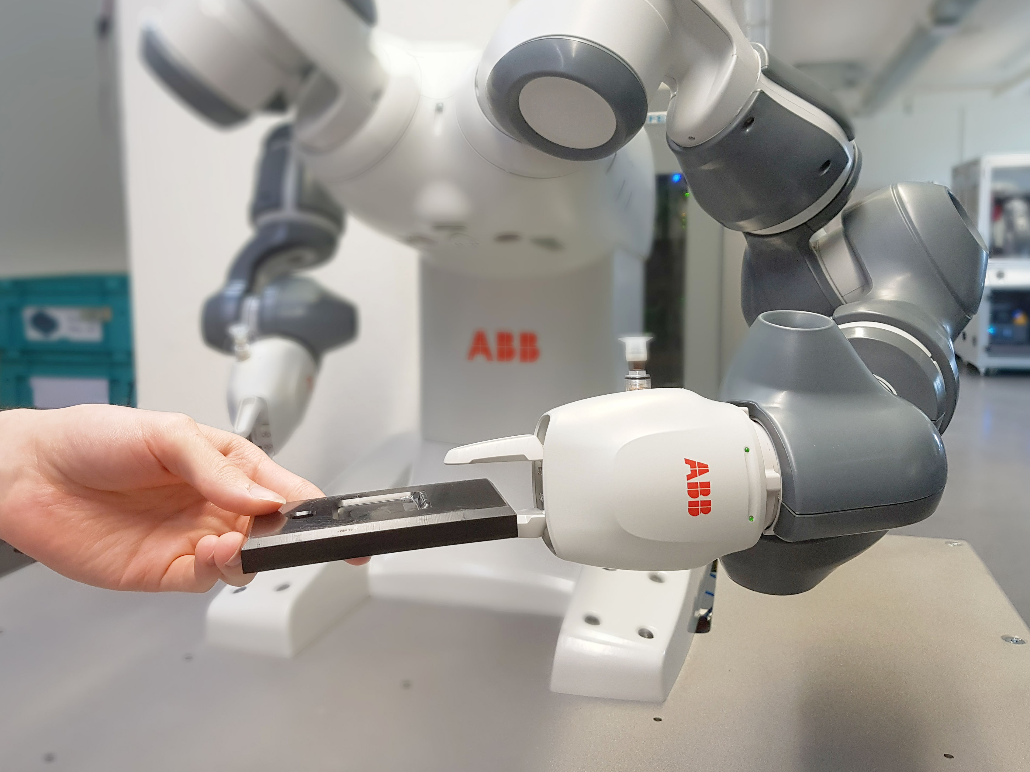 [Translate to English:] Mitarbeiter reicht einem Roboter eine Gehäuseunterschale
