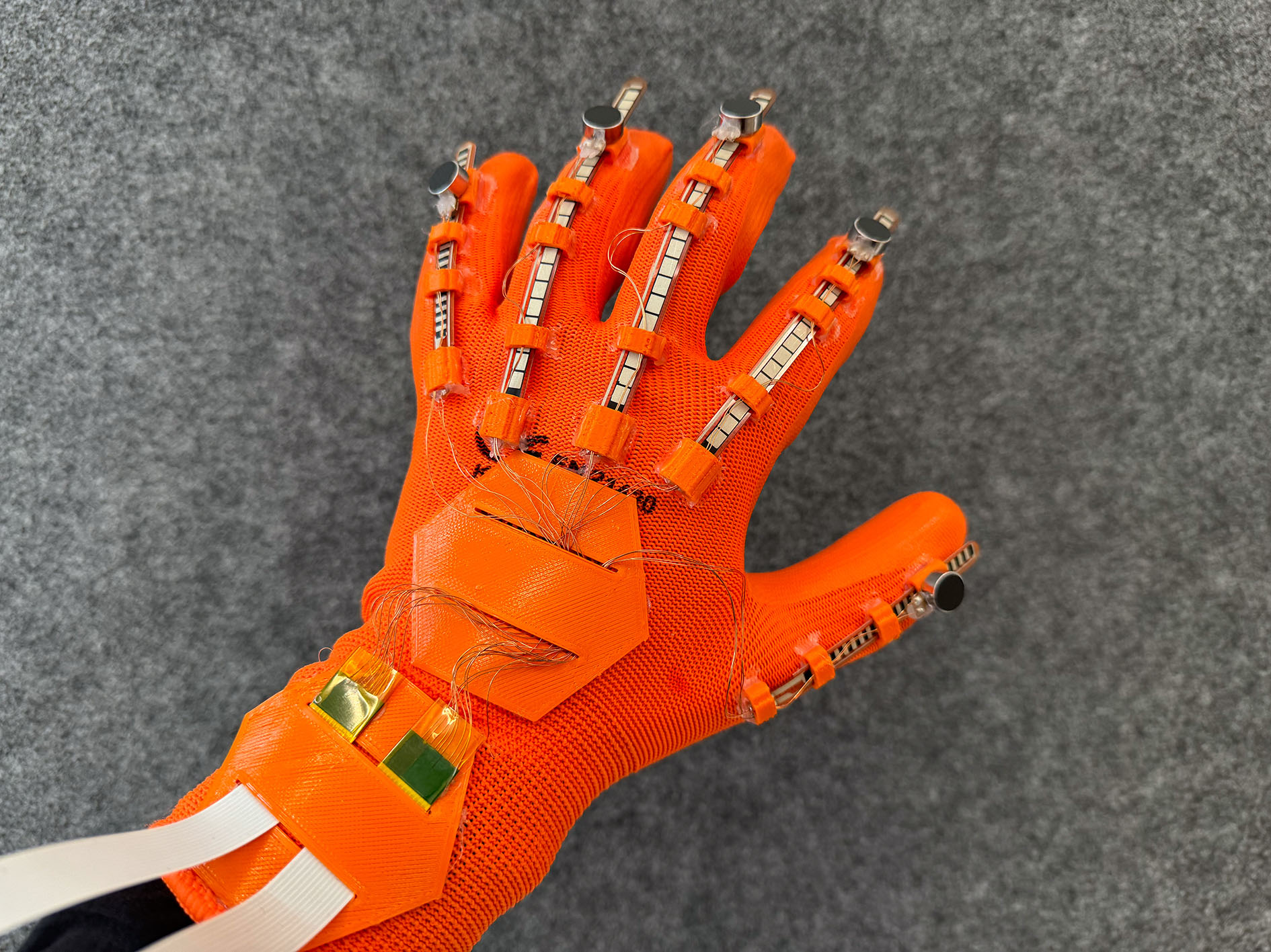 ein textiler Handschuh mit angenähten Sensoren und verbindende Elektronik ist von oben zu sehen