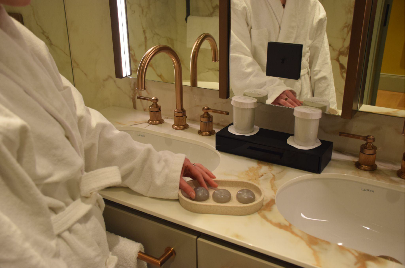 eine Hand greift neben einem Waschbecken nach einer Shampoo Bubblenach