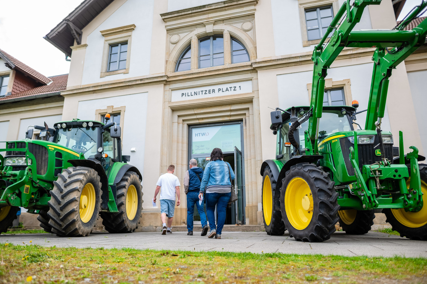 Traktoren und Besucher vor einem Gebäude der Fakultät