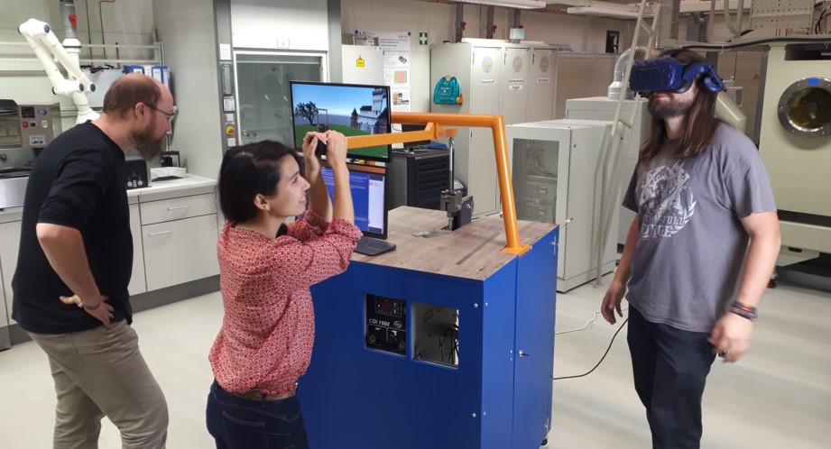 Personen betrachten ein Exponat, eine Person trägt eine VR-Brille