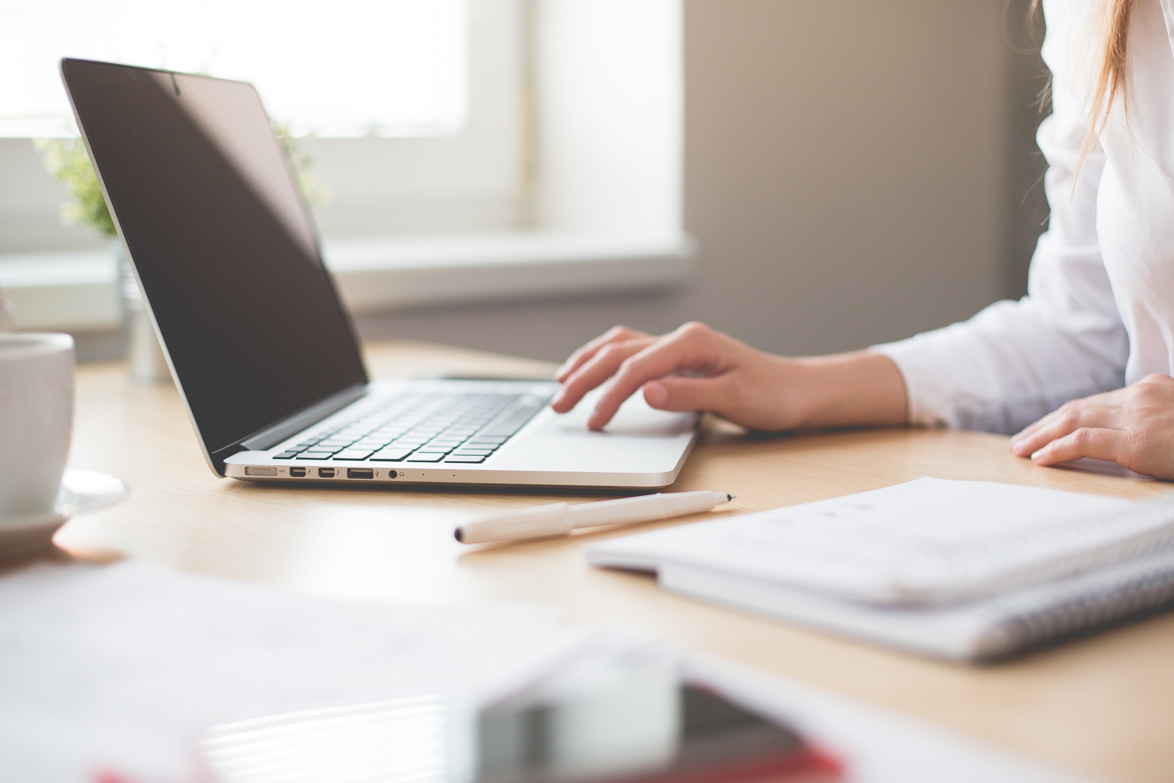 Schreiben einer Arbeit am Laptop und Notizen auf Papier