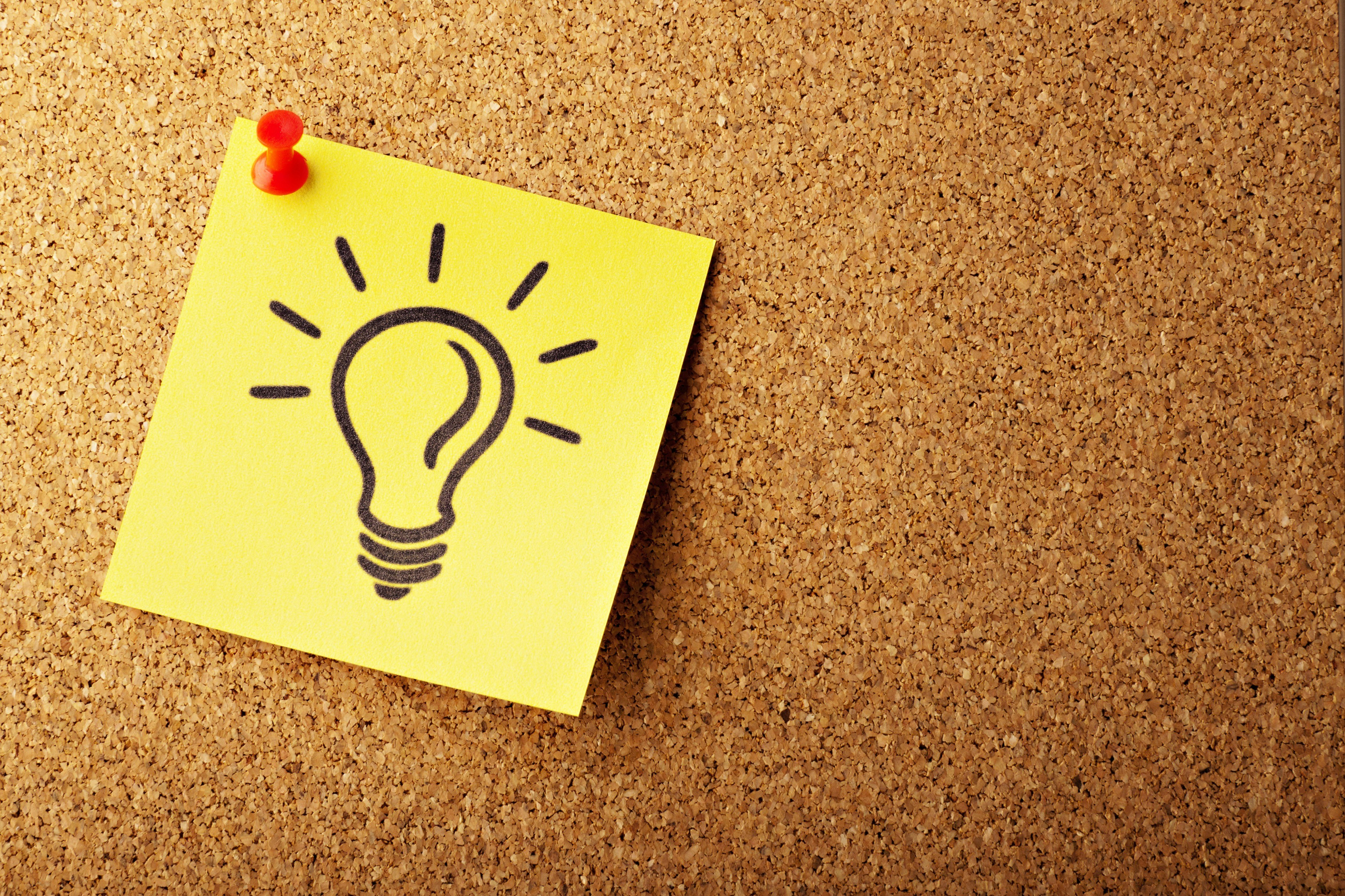 Postit mit Glühbirne auf Korkwand