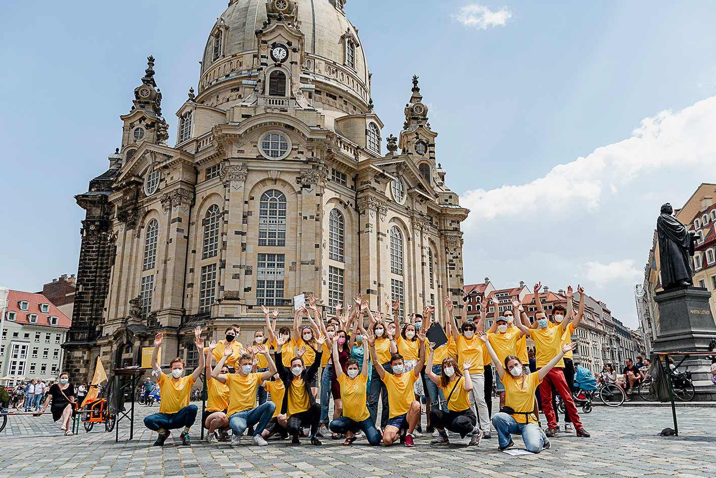 Menschen vor der Frauenkirche in Dresden, die die Hände heben