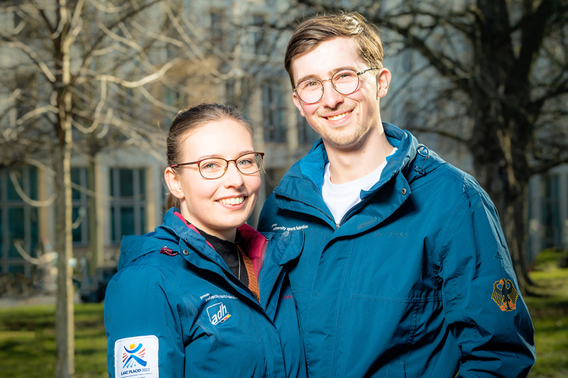 Eistanzpaar Charise Matthaei und Max Liebers lächelnd vor dem Hauptgebäude der Hochschule fotografiert