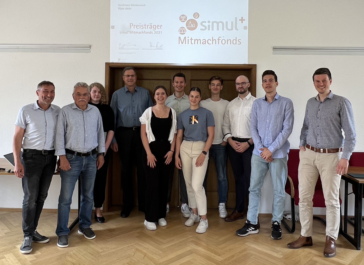eine Gruppe junger Menschen stehen vor einer Präsentation mit simul-Logo