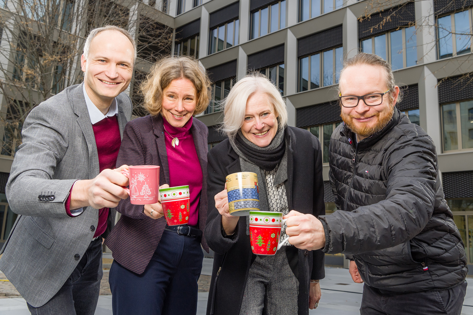 Hochschulleitung hält Weihnachtstassen hoch