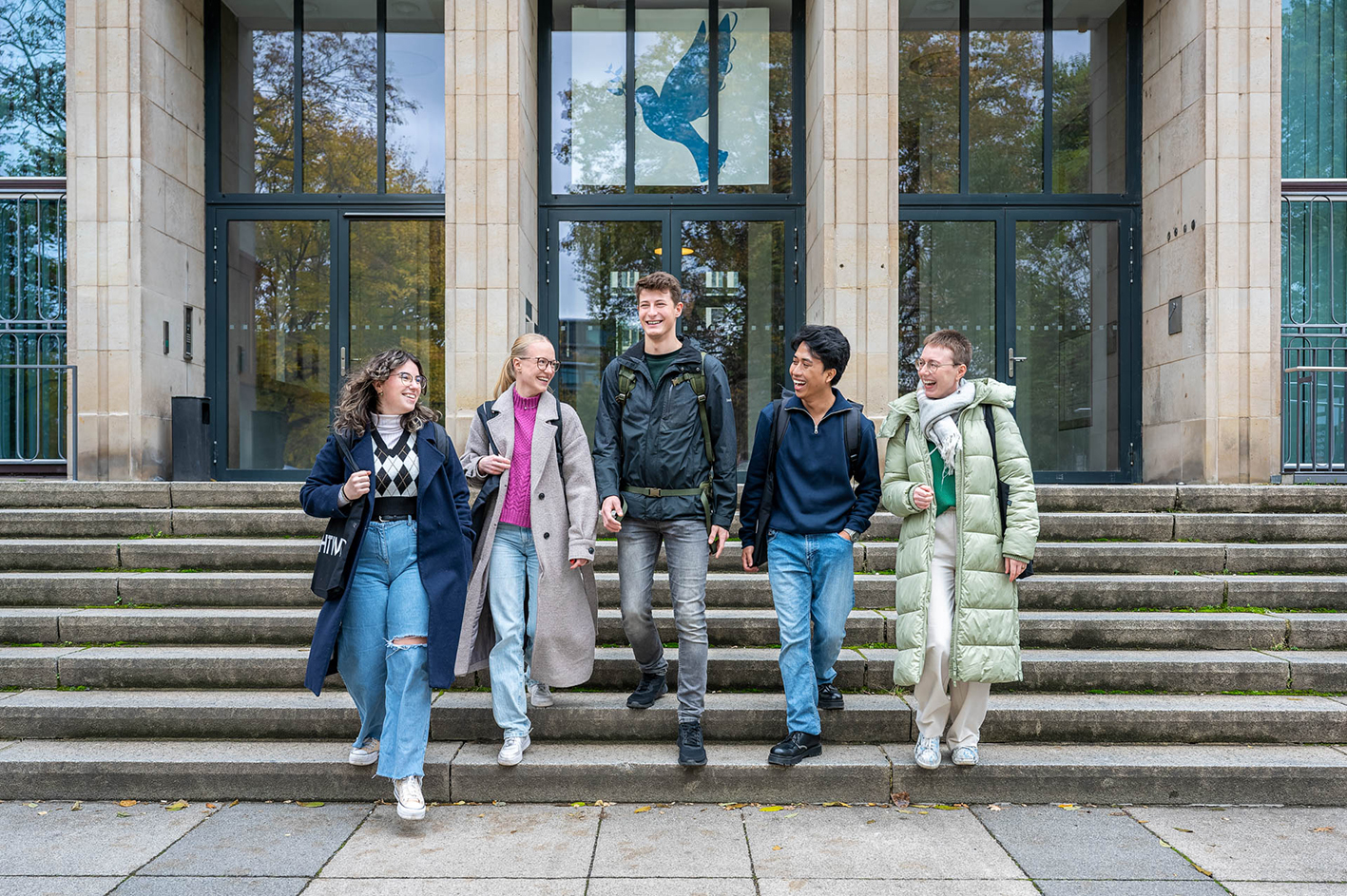 fünf junge Menschen laufen die Treppe vorm Hauptgebäude der HTWD hinunter