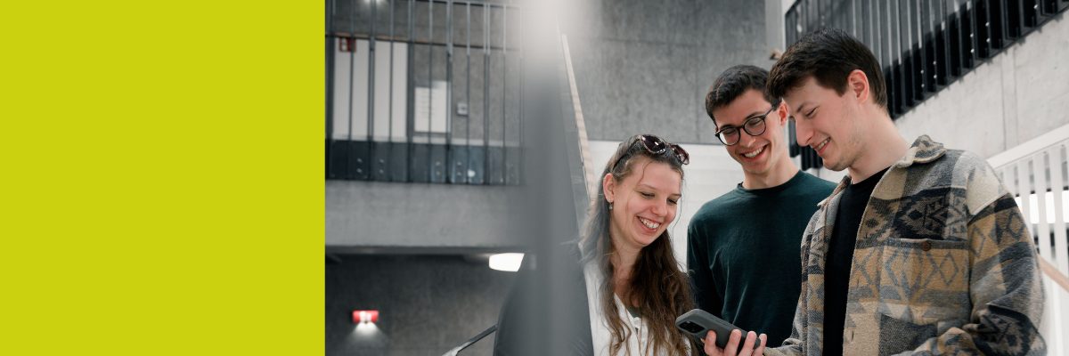 Drei junge Menschen schauen auf ein Mobiltelefon