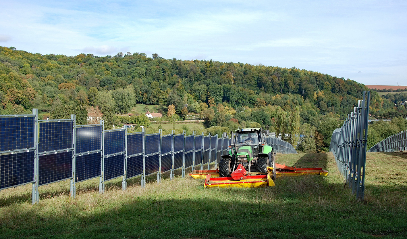 Traktor auf einer Wiese zwischen Agri-PV-Anlagen