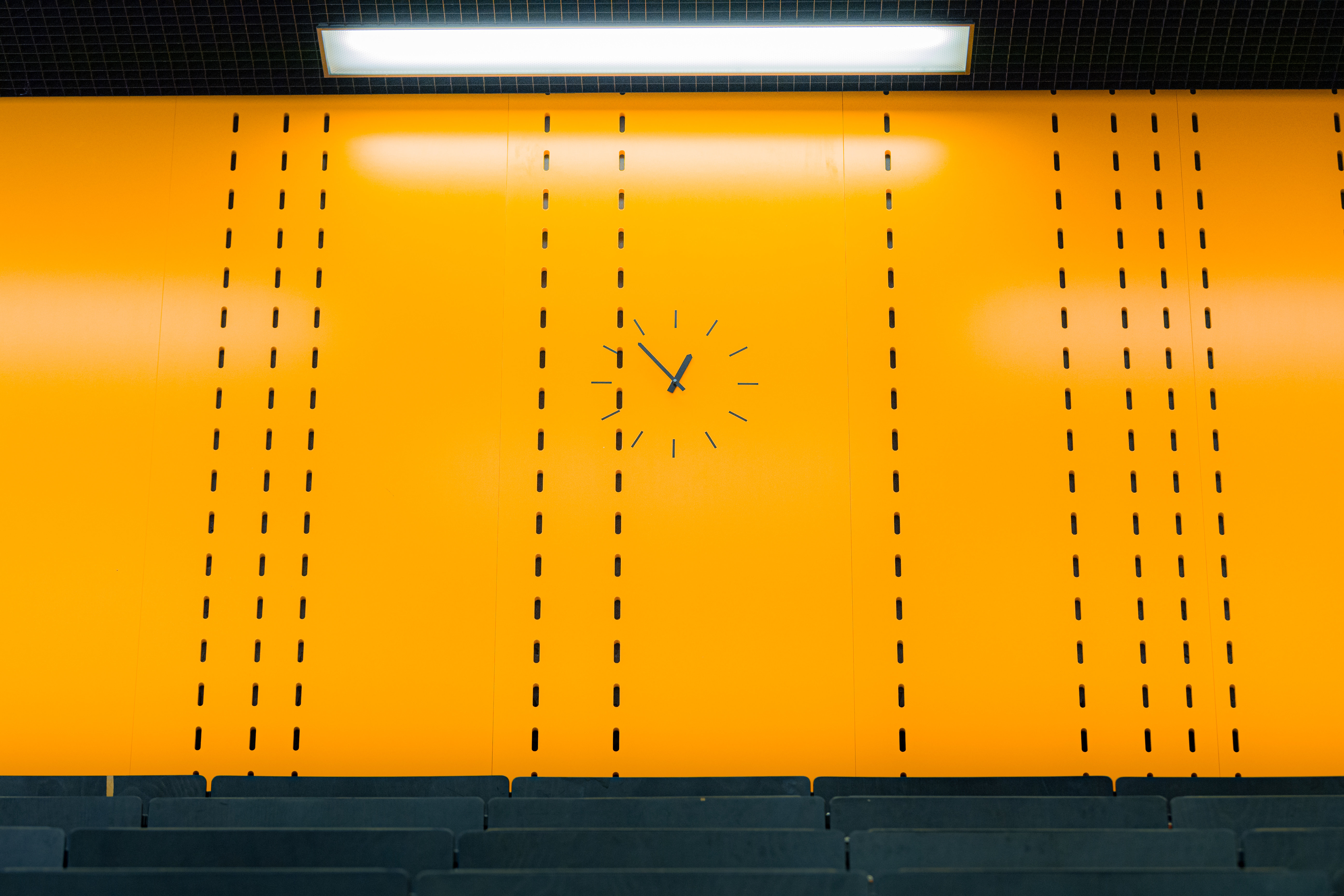 Uhr im Hörsaal vor oranger Wand