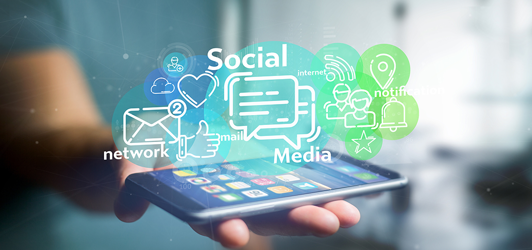 Eine Hand hält ein Handy mit Social Media Icons