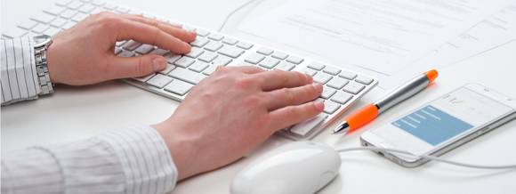 [Translate to English:] Desk situation, writing on a computer keyboard