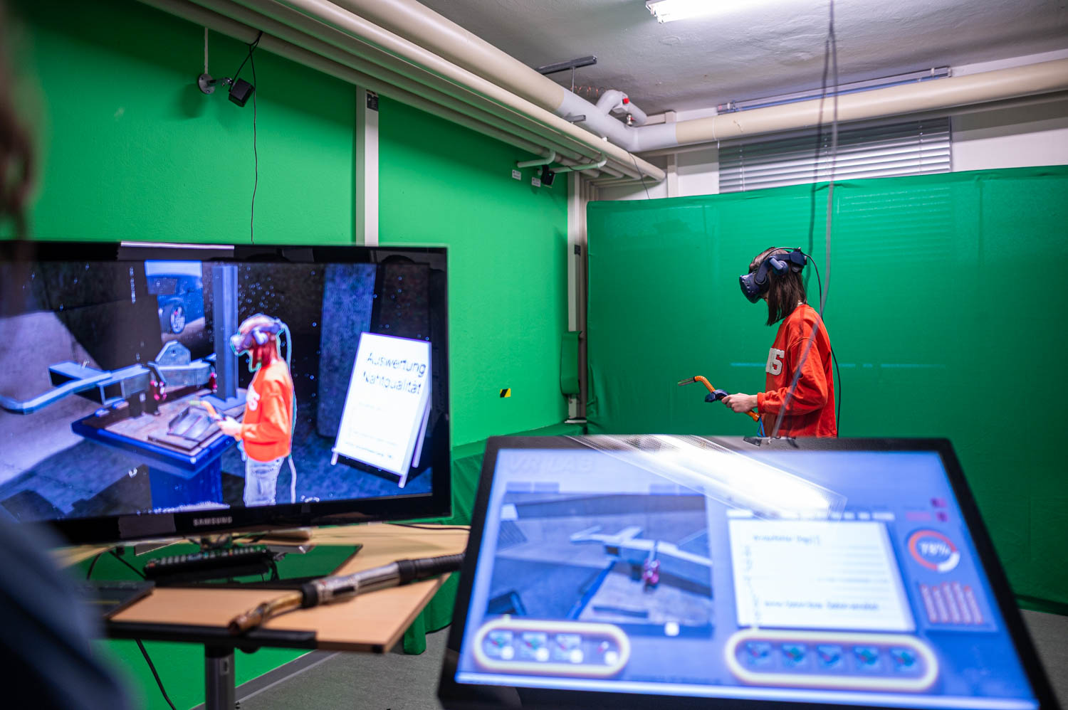 Person mit VR-Brille hinter Bildschirmen