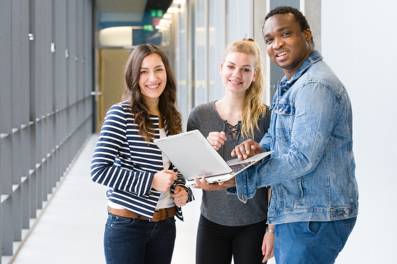 Three students are standing in the teaching building