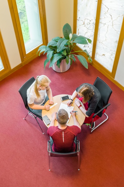 [Translate to English:] Studierende im Gespräch am runden Tisch