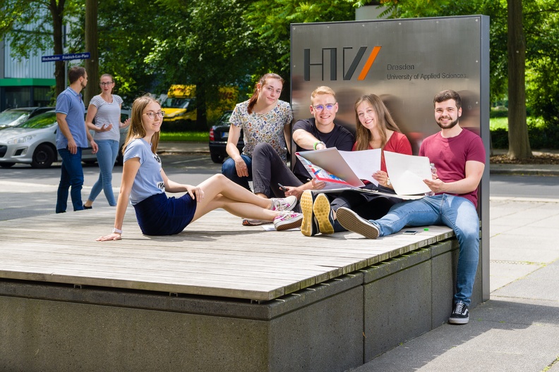 Group of students sit in front of the campus