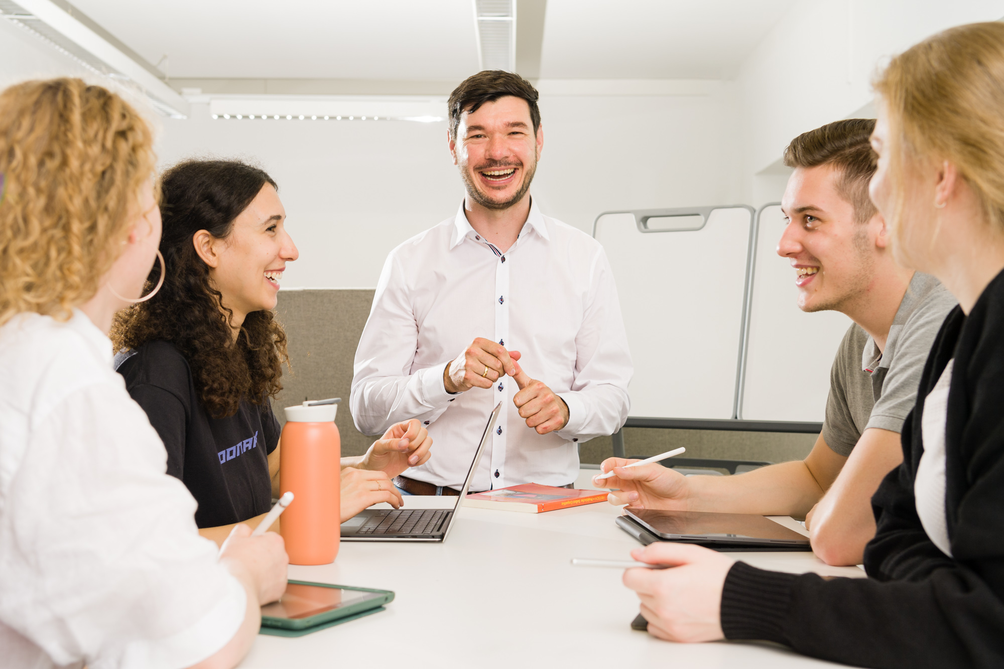 Professor laughs directly into the camera around him Students