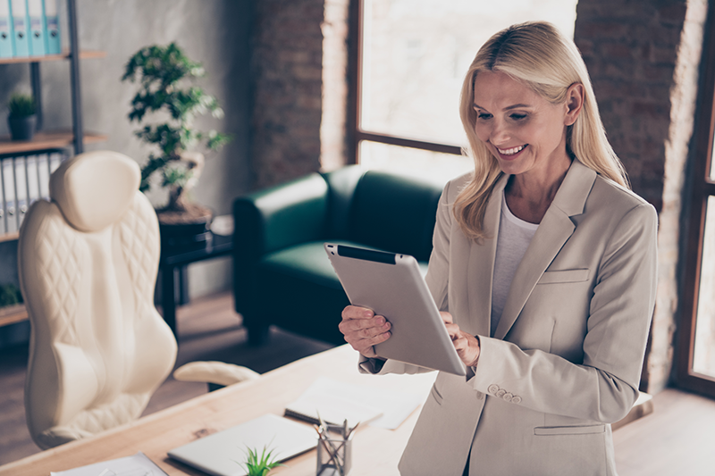 [Translate to English:] Unternehmerin liest auf ihrem Tablet aktuelle News des Alumni-Netzwerkes