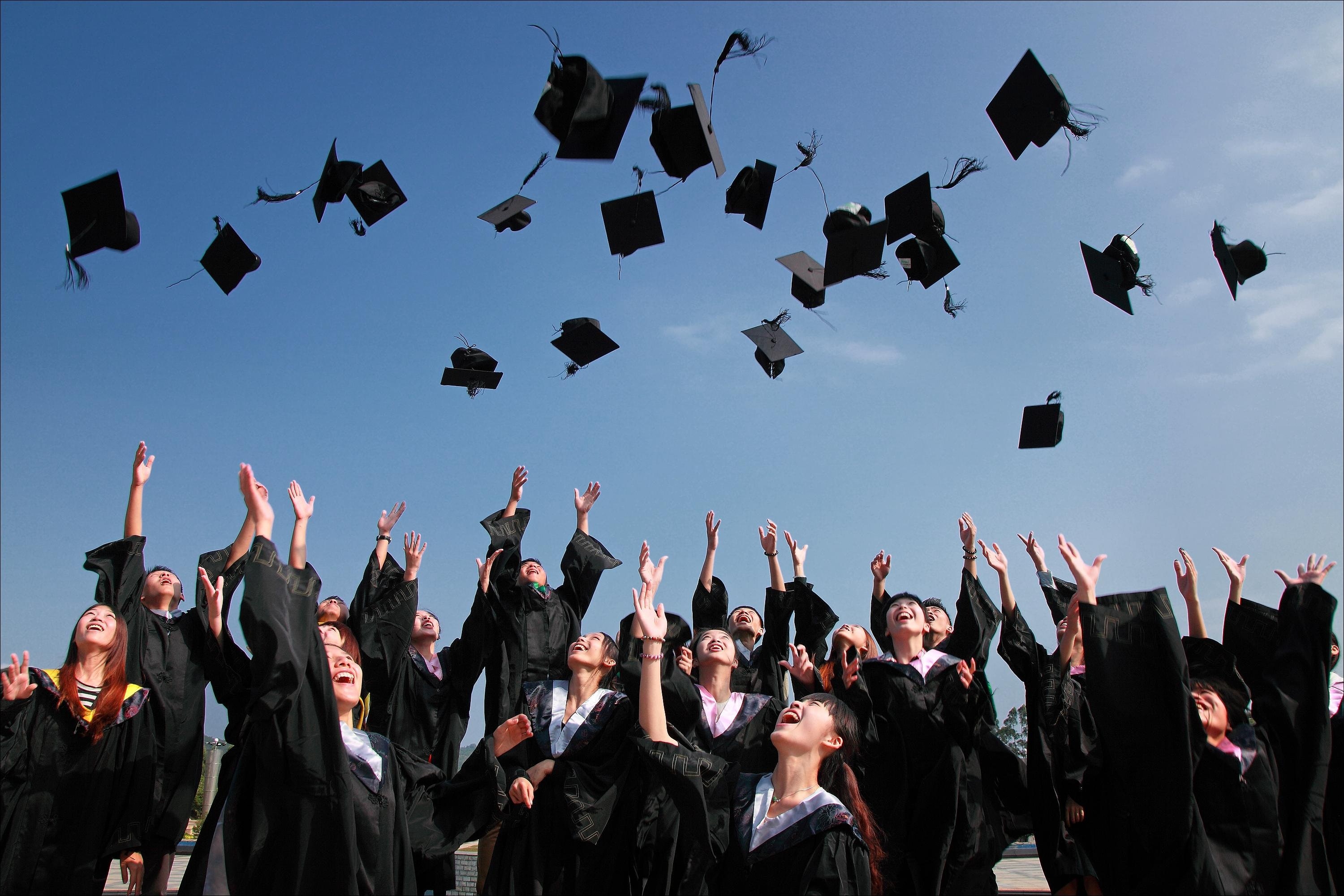 Graduates throw doctoral hats into the air