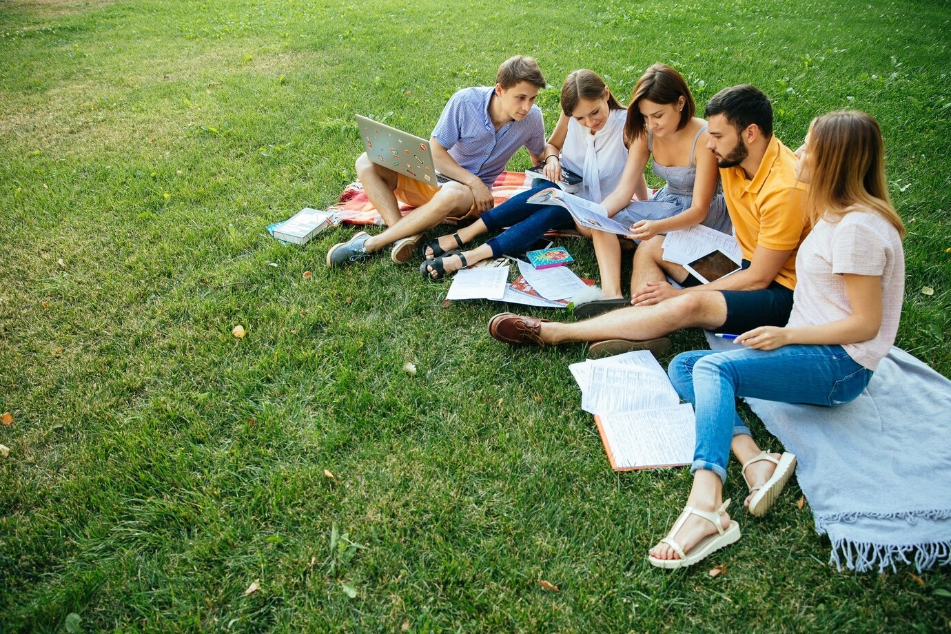 Studierendengruppe im Gras sitzend