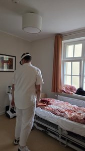 Pflegekraft beim Ausprobieren einer Augmented-Reality-Brille vor einem Bed