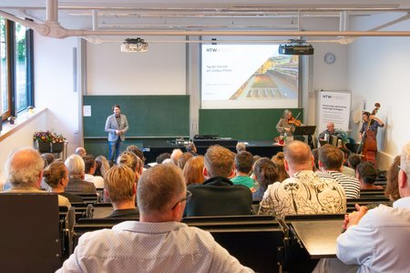 Ein Mann, der auf der Bühne vor einem Publikum steht.