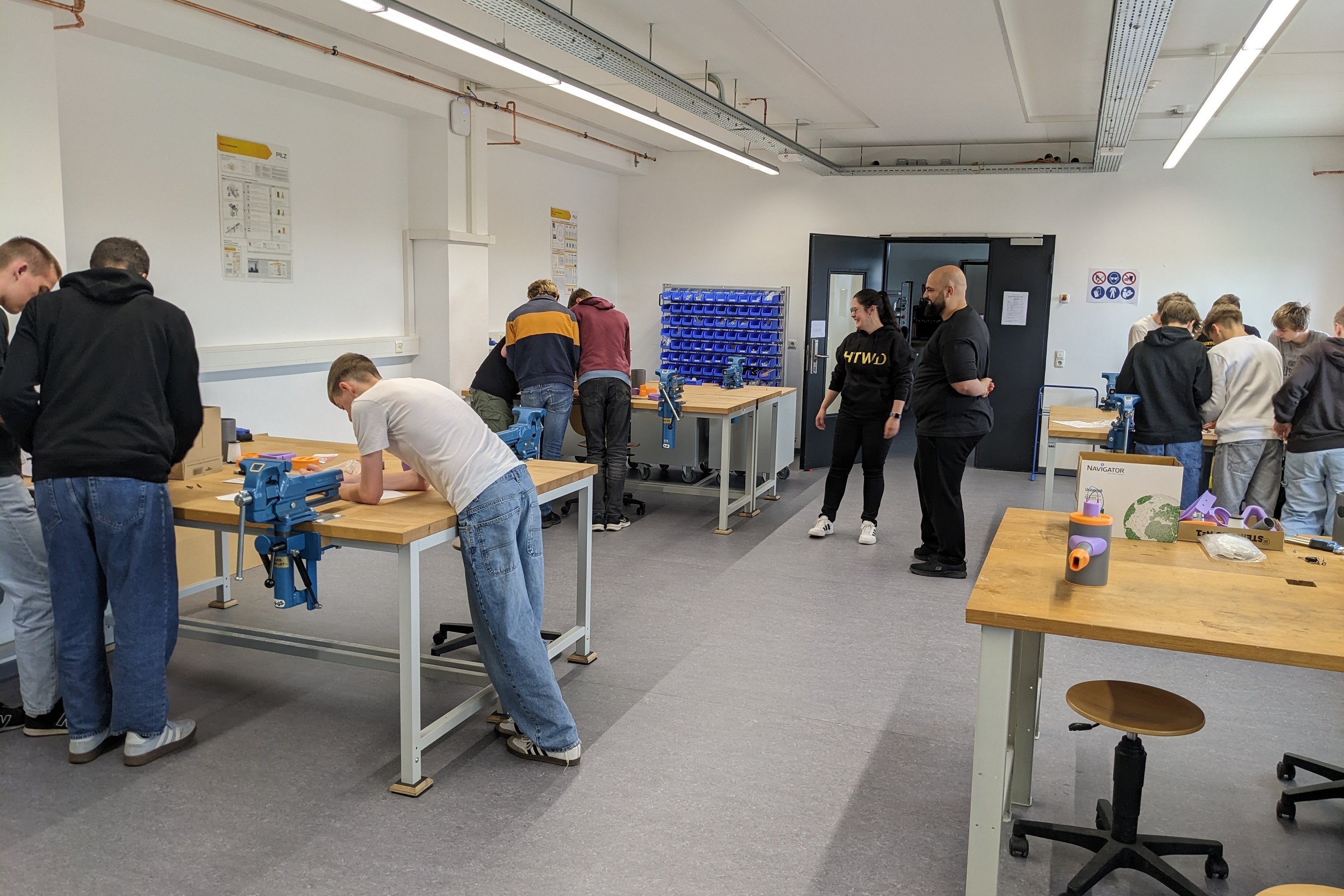 Blick in den Raum des Workshops, mehrer Gruppen an verschiedenen Tischen beim Bauen