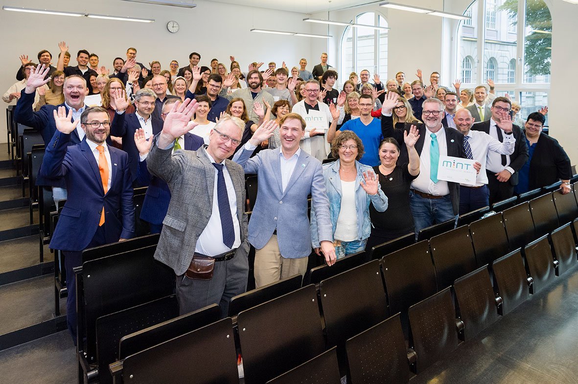 Menschen winkend im Hörsaal