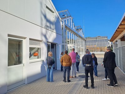 10 Personen stehen vor zwei Glashäusern