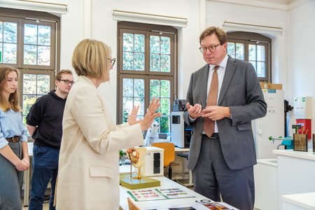 Eine Professorin erklärt dem Minister etwas über ihre Forschung.