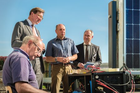 Vier Männer, die eine kleine Forschung Agri-PV-Anlage anschauen