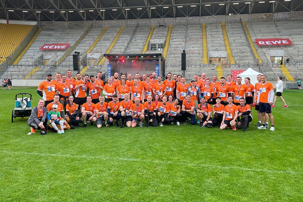 Das Team der HTWD in organgefarbenen Trikots im Rudolf Harbig Stadion