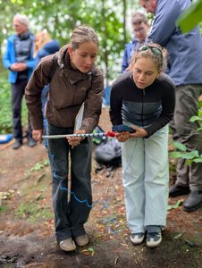 Schülerinnen schauen auf ein Messgerät im Wald