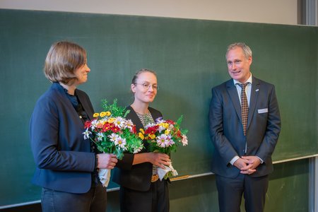 Zwei Frauen mit Blumenstrauß und ein Mann