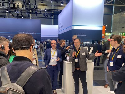 Eine Person steht mit einem Mikrophon vor dem Messestand