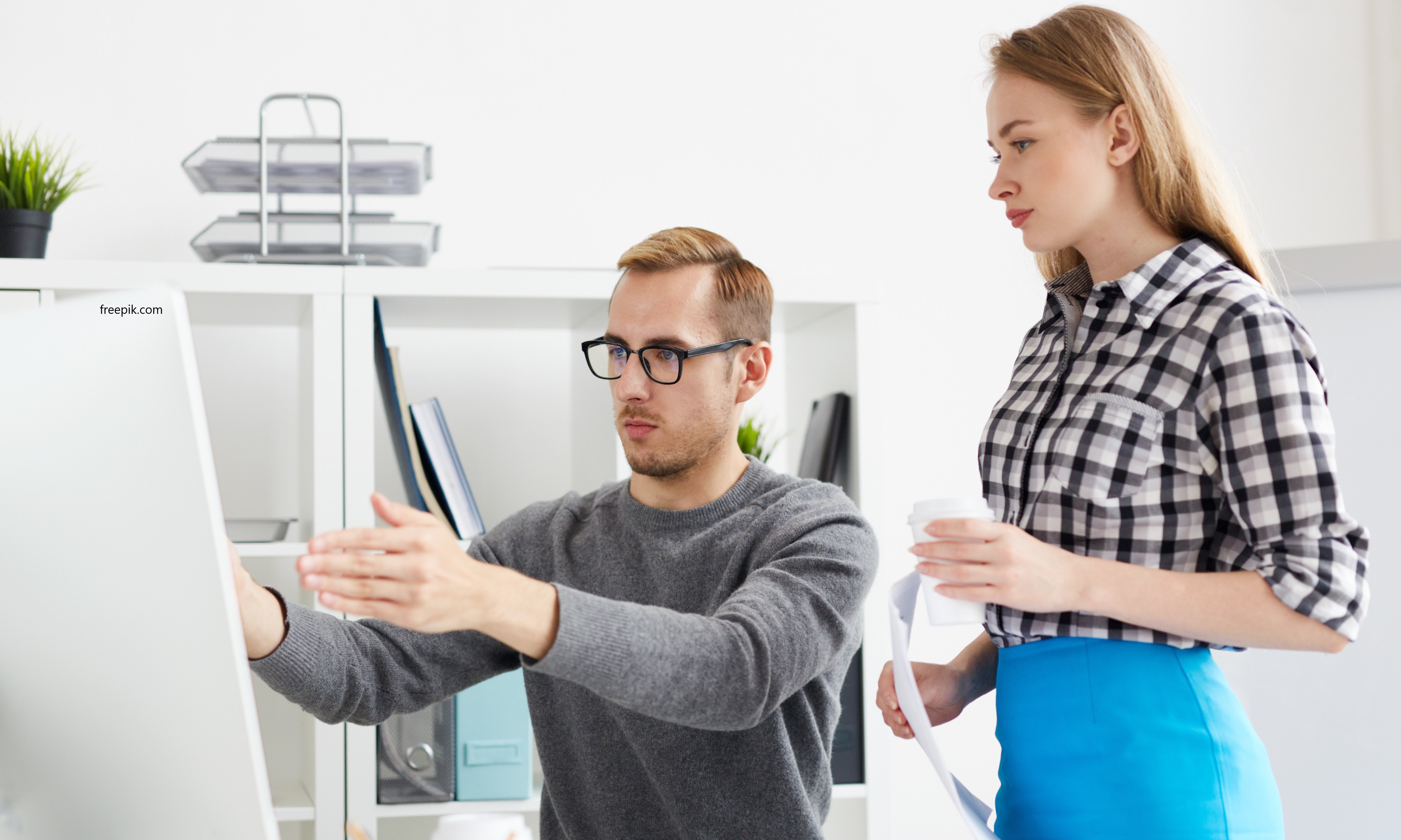 zwei Personen betrachten einenComputerarbeitsplatz