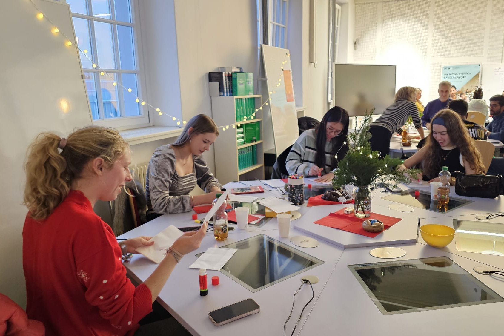 Studierende sitzen um einen Tisch und basteln Weihnachtssterne