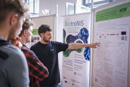 Ein Mann, der zwei Studenten etwas erzählt.