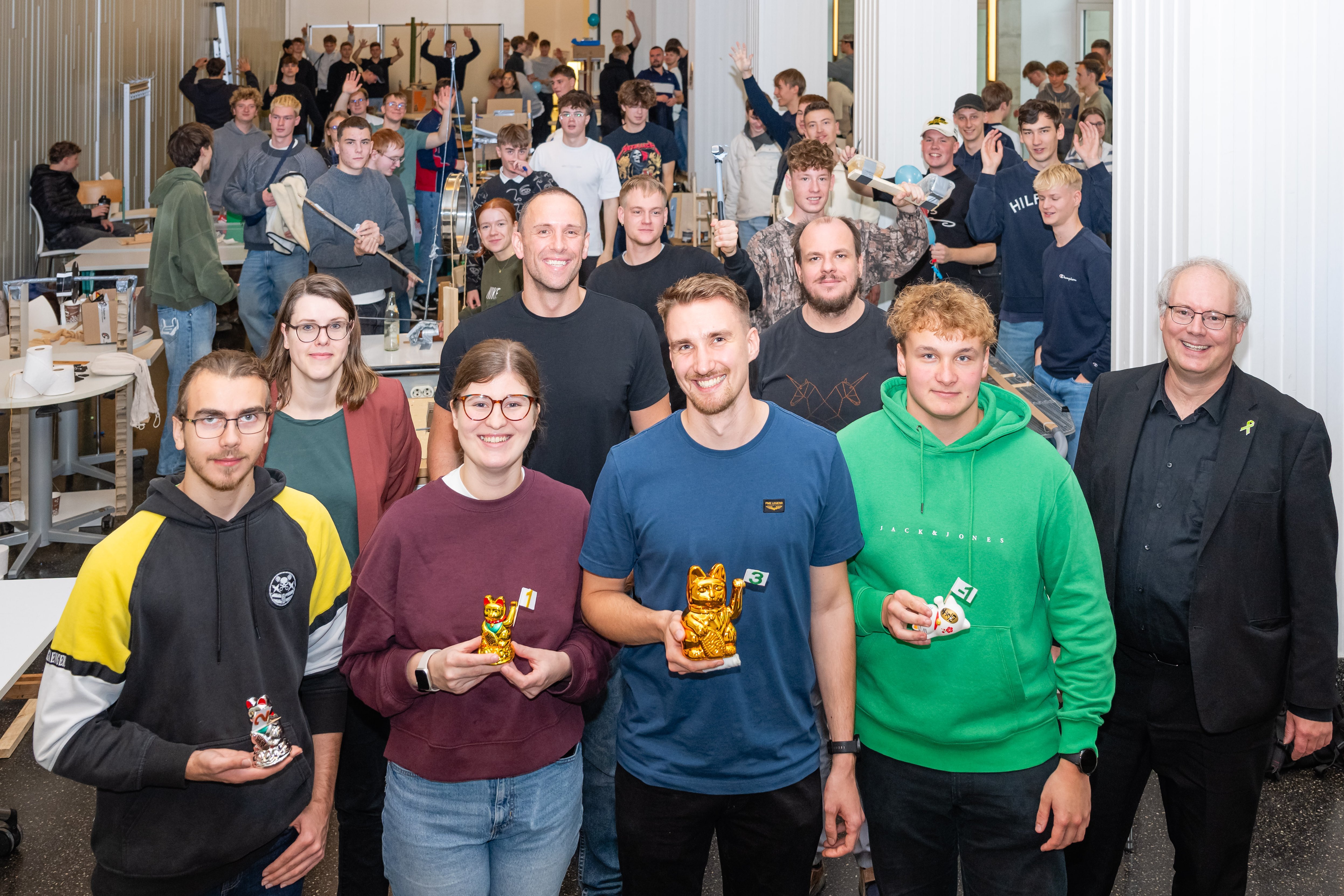 Die Gewinner halten die Glückskatzen in den Händen.