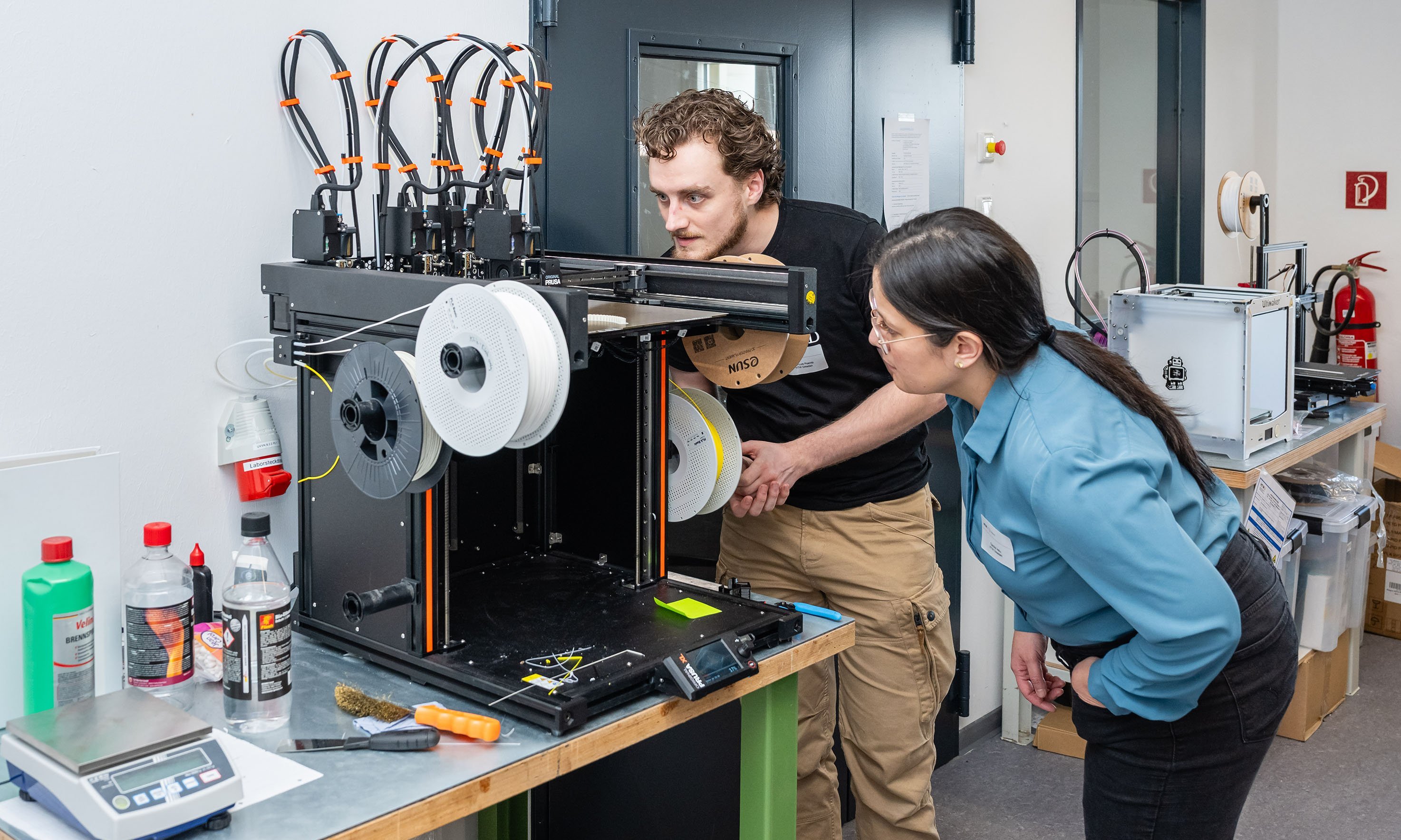 Zwei Menschen schauen in einen 3D Drucker