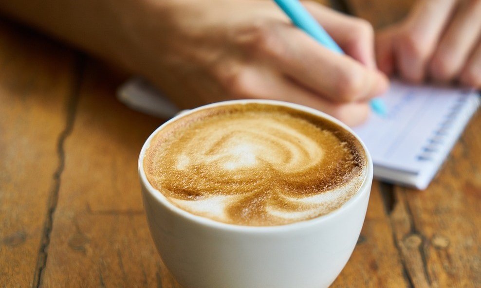 Tasse Kaffee mit Notizblock und Stift