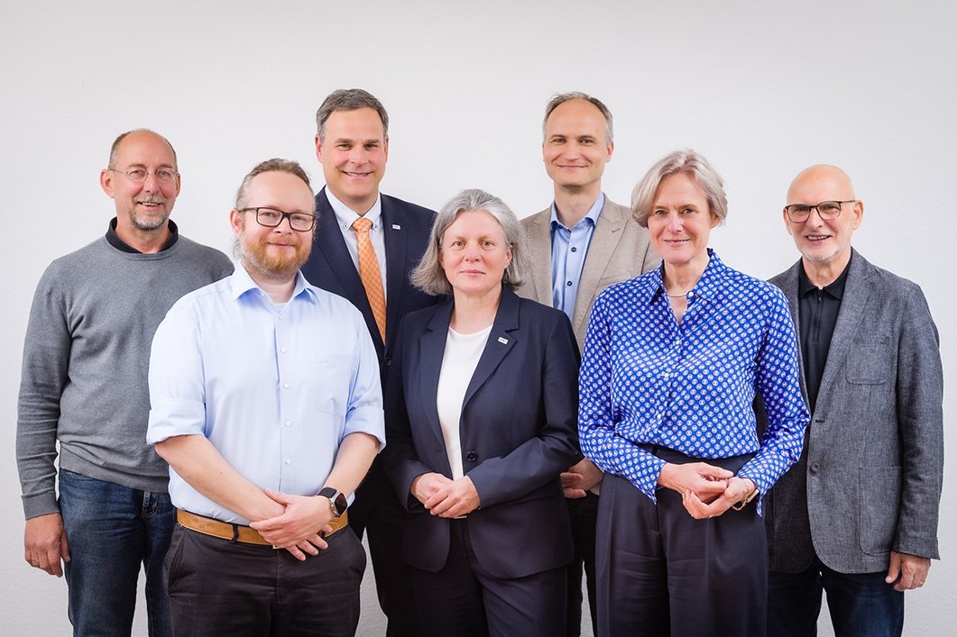 Eine Gruppe von Männern und Frauen blicken lächelnd in die Kamera
