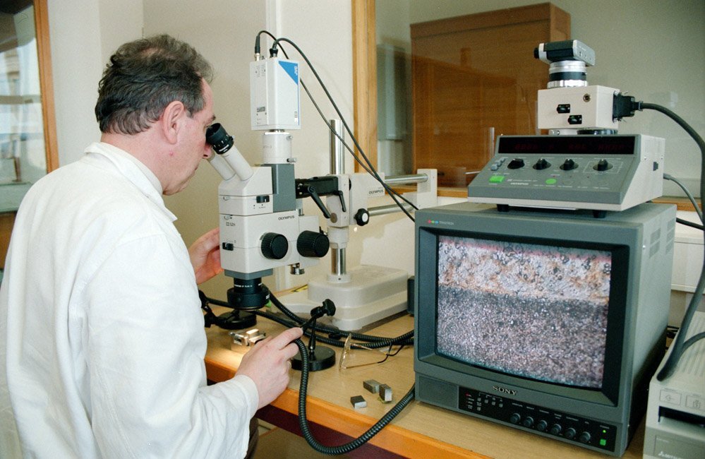 Mann untersucht Material unter einem Mikroskop im Labor für Werkstoffwissenschaften