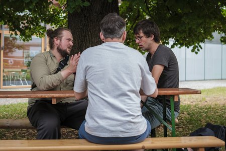 Menschen, die an einer Biertisch-Garnitur sitzen.