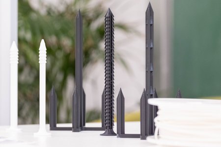 Schwarze und weiße Schrauben mit Haken aus Kunststoff, die auf einem Tisch stehen.